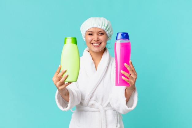 Młoda ładna kobieta ubrana w szlafrok i trzymająca czystą butelkę produktu