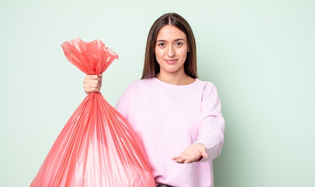 Młoda ładna kobieta uśmiecha się szczęśliwie z przyjazną, oferującą i pokazującą koncepcję. koncepcja śmieci