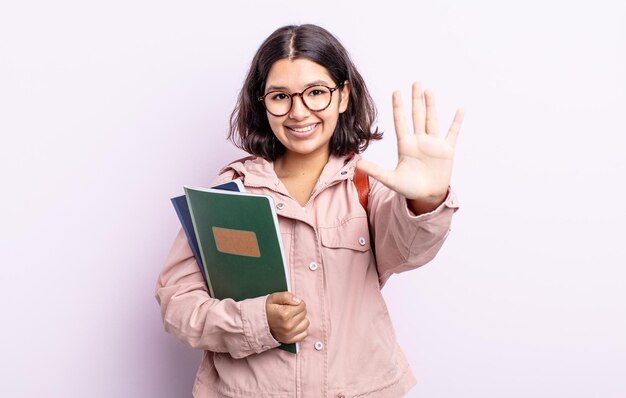 Młoda, ładna Kobieta, Uśmiechnięta I Przyjazna, Pokazująca Numer Pięć. Student Z Koncepcją Książek