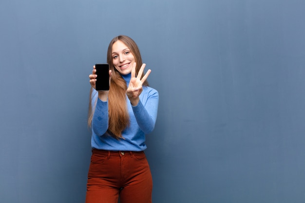 Młoda ładna Kobieta Używa Mądrze Telefon Na Błękit ścianie Z Odbitkową Przestrzenią