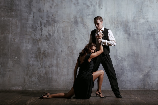 Młoda ładna kobieta w czarnej sukni i tango tańca człowieka