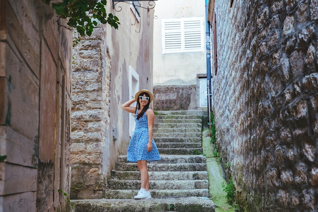 Młoda ładna kobieta w niebieskiej sukience spacerująca uliczkami Herceg Novi. koncepcja wakacji letnich