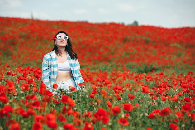 Młoda ładna kobieta w okularach przeciwsłonecznych na polu kwiatów maku