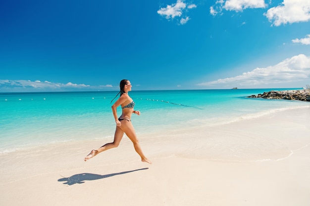Młoda ładna kobieta z pięknym ciałem w stroju kąpielowym w słoneczny dzień wody oceanu w koncepcji odnowy biologicznej na tropikalnej plaży