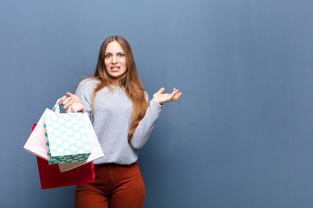 Młoda ładna kobieta z torba na zakupy przeciw błękit ścianie z odbitkową przestrzenią