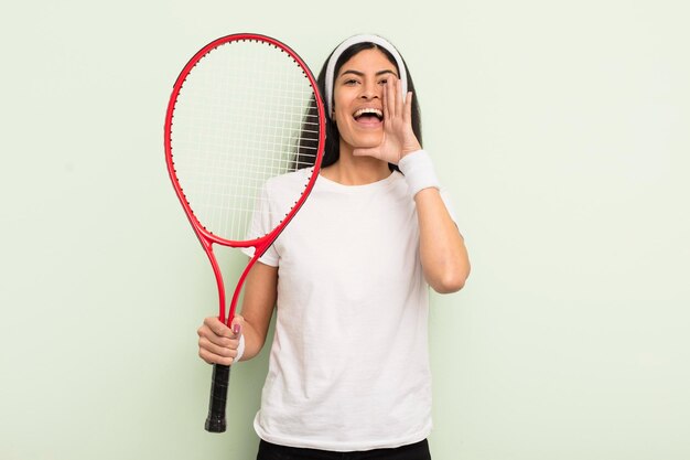 Młoda ładna latynoska kobieta czuje się szczęśliwa, dając wielki okrzyk z rękami przy ustach koncepcji tenisa