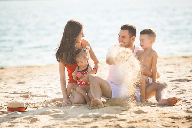 Młoda ładna matka bawić się z jej małą śliczną córką na plaży. Kochająca mama zabawy z dzieckiem na brzegu morza