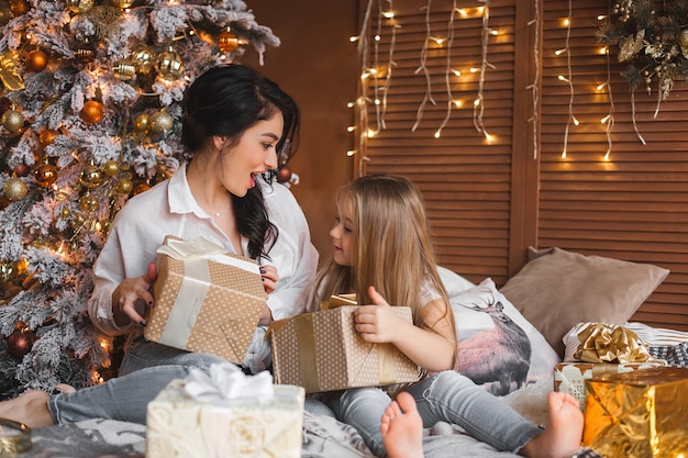 Młoda ładna matka i jej córeczka dzielą prezenty świąteczne