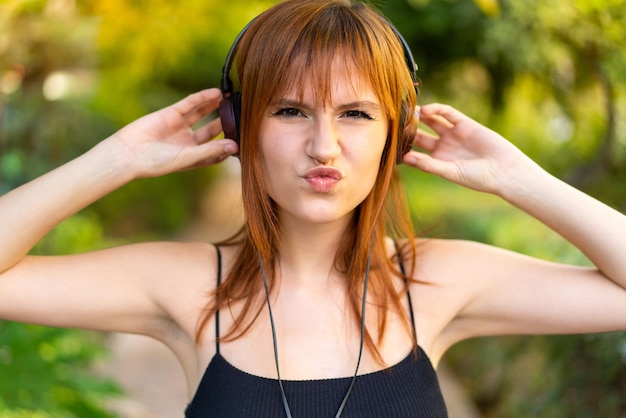 Młoda ładna ruda kobieta na świeżym powietrzu słucha muzyki