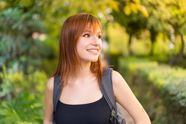 Młoda ładna rudowłosa kobieta na zewnątrz Ze szczęśliwym wyrazem twarzy