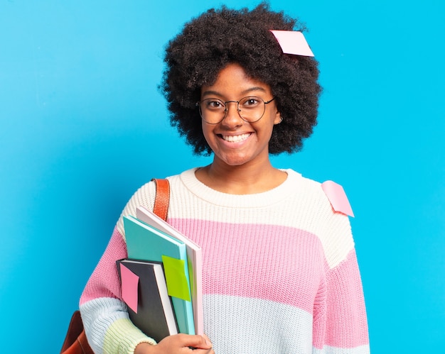 Młoda ładna studentka afro kobieta trzyma zeszyty