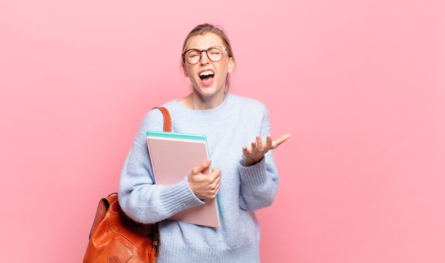 młoda ładna studentka wyglądająca na zdesperowaną i sfrustrowaną, zestresowaną, nieszczęśliwą i zirytowaną, krzyczącą i krzyczącą