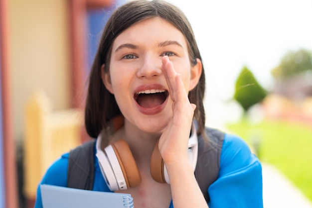 Młoda ładna ukraińska studentka na zewnątrz krzycząca z szeroko otwartymi ustami