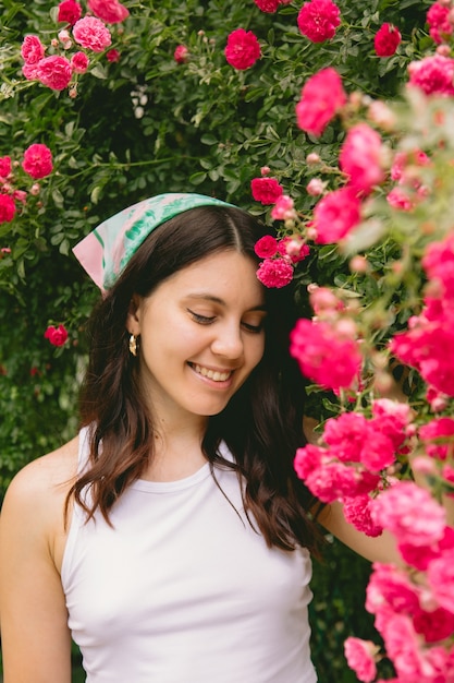 Młoda ładna uśmiechnięta kobieta w pobliżu kwitnących czerwonych róż krzak miejsca kopiowania