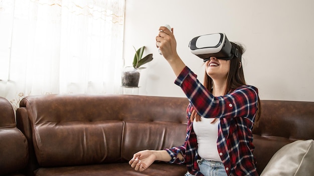 Młoda latynoska kobieta bawi się w domu w okularach wirtualnej rzeczywistości