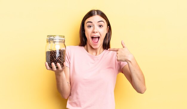 Młoda latynoska kobieta czuje się szczęśliwa i wskazuje na siebie z podekscytowaniem. koncepcja ziaren kawy