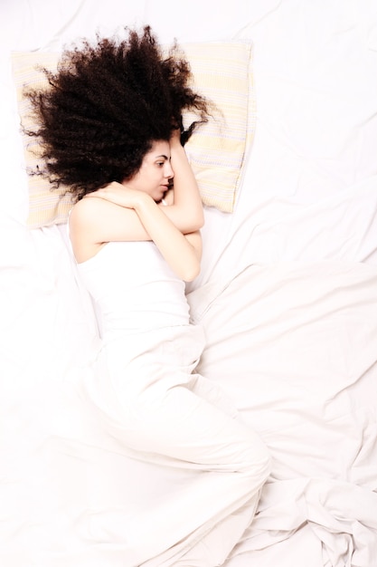 Zdjęcie młoda latynoska kobieta, leżąc w łóżku.