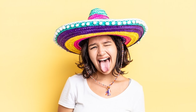 Młoda latynoska kobieta o pogodnym i buntowniczym nastawieniu, żartuje i wystawia język. koncepcja meksykańskiego kapelusza