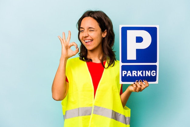 Młoda Latynoska Kobieta Trzyma Tabliczkę Parkingową Na Białym Tle Na Niebieskim Tle
