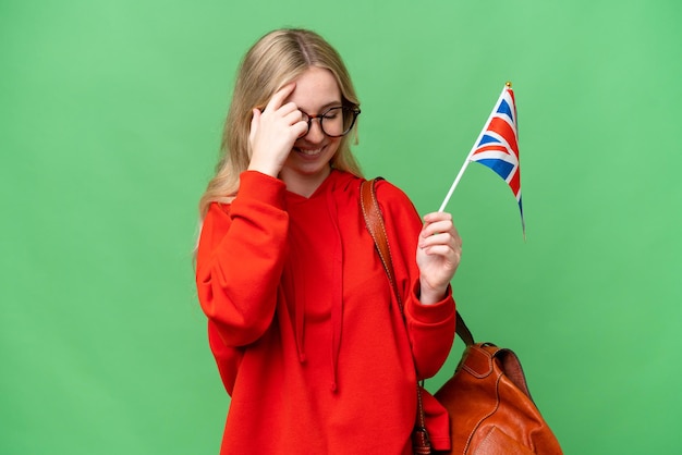 Młoda latynoska kobieta trzymająca flagę Wielkiej Brytanii na odizolowanym tle śmieje się