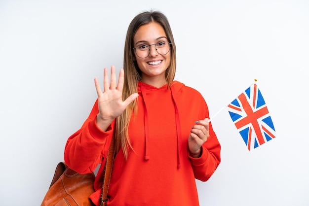 Młoda latynoska kobieta trzymająca flagę Wielkiej Brytanii odizolowana na białym tle, licząca pięć palcami