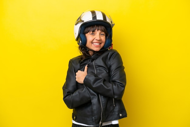 Młoda latynoska kobieta z kaskiem motocyklowym na żółtym tle