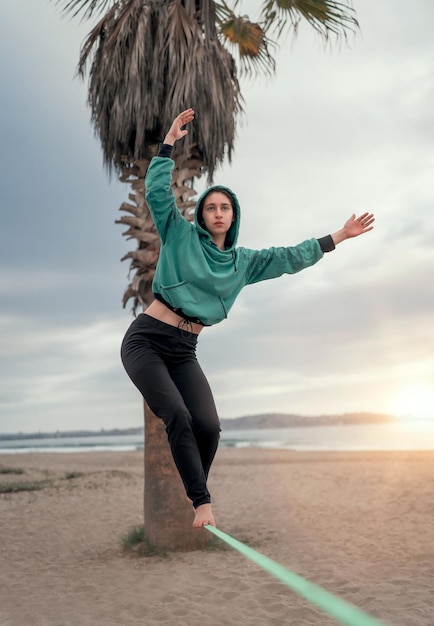 Młoda Latynoska spaceruje i balansuje na luźnej taśmie do jogi na plaży La Serena