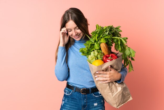Młoda litewska kobieta śmieje się trzymając torbę na zakupy spożywcze