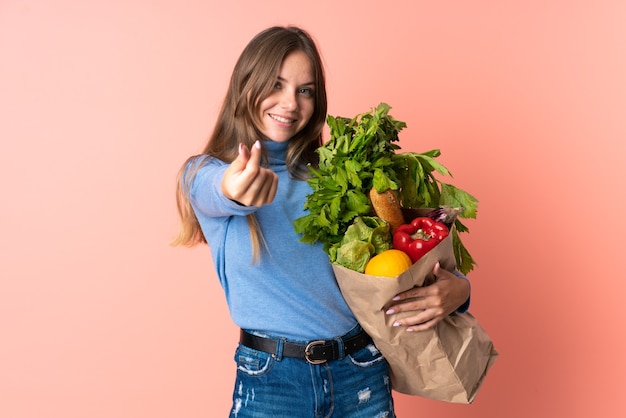 Młoda litewska kobieta trzyma torbę na zakupy spożywcze, czyniąc gest pieniędzy