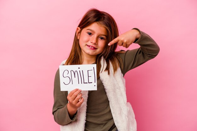 Młoda mała dziewczynka trzyma sztandar uśmiech na różowym tle