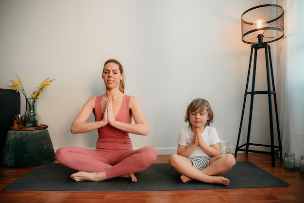 Młoda mama i syn ćwiczą jogę w domu
