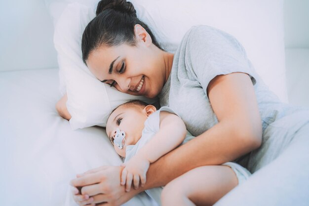 Młoda mama ma delikatny moment z synem w łóżku w domu - Skup się na twarzy dziecka