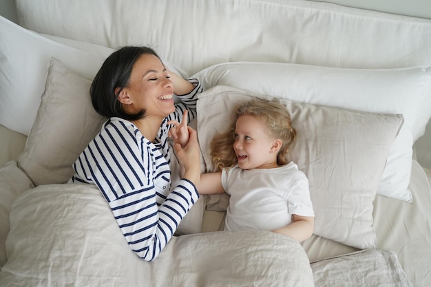 Młoda mama odpoczywa z córeczką w sypialni Koncepcja rodzicielstwa i relacji