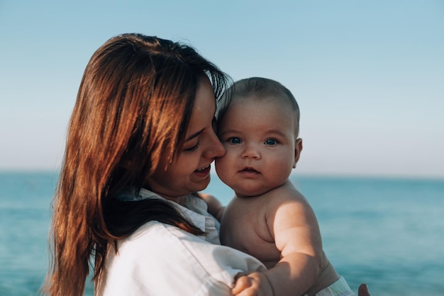 Młoda mama spaceruje po plaży z małym dzieckiem w pieluchach