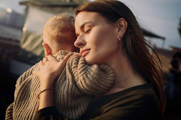 młoda mama z zamkniętymi oczami przytula synka kładącego głowę na jej ramieniu