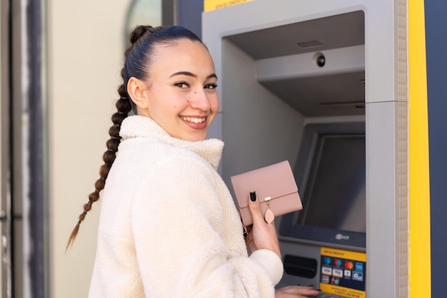 Młoda marokańska dziewczyna na zewnątrz za pomocą bankomatu