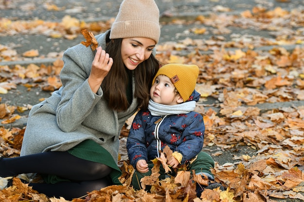 Młoda matka bawi się małym dzieckiem w jesiennym parku.