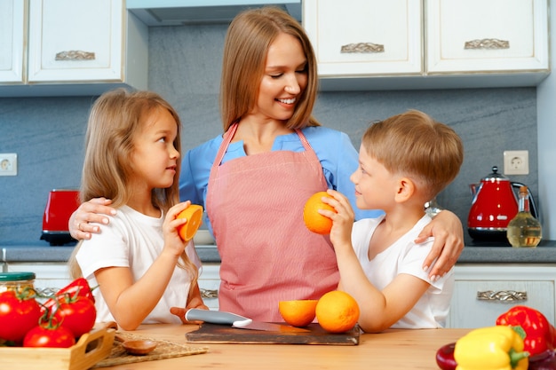 Młoda matka gotuje z dziećmi w kuchni