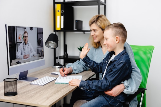 Młoda matka i dziecko cieszące się epoką cyfrową korzystają z internetowych konsultacji telemedycznych z zdalnym lekarzem przez profesjonalnego pediatrę w zakresie leczenia wirusa przeziębienia i grypy