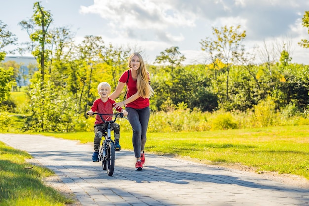 Młoda matka uczy syna jeździć na rowerze w parku.