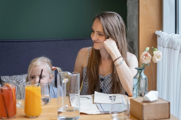 Młoda matka z córką siedzą przy stole w kawiarni Mama odpoczywa w restauracji ze swoją małą córeczką