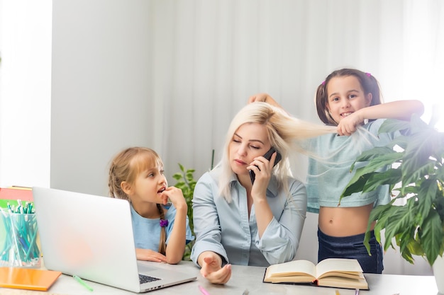 Młoda matka z dwójką dzieci pracuje w domu na komputerze. Zmęczenie Styl życia Gospodyni niezależna. zmęczona mama i dwie córeczki