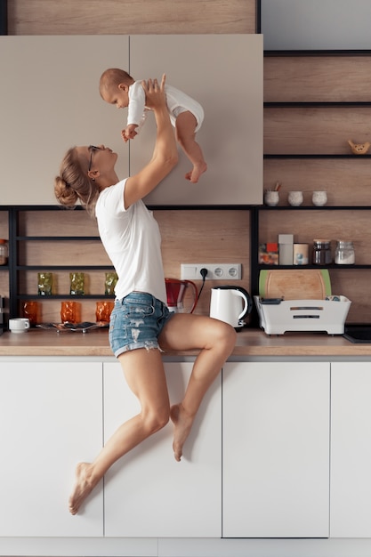 Młoda matka z dzieckiem bawić się w kuchni w domu