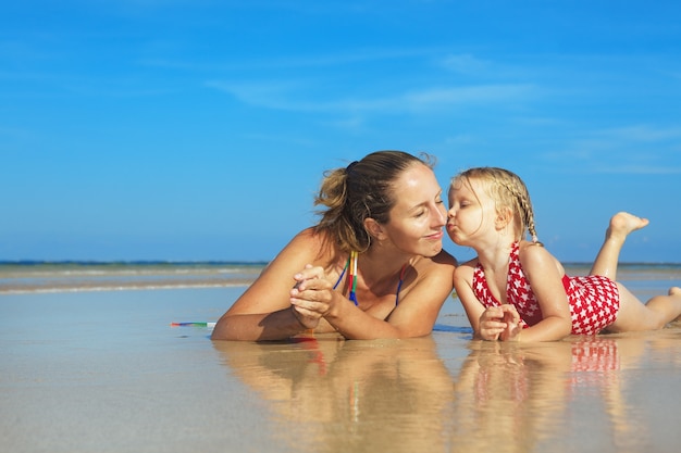 Zdjęcie młoda matka z dzieckiem leżącym w wodzie na tropikalnej plaży