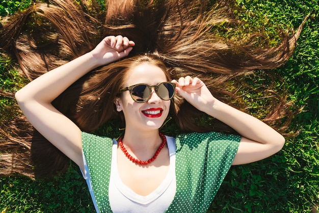 Młoda moda letnia dziewczyna w sukience leżącej na trawie. Widok powyżej, retro, vintage