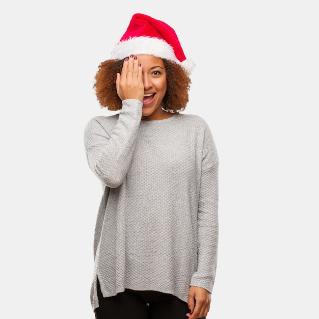Młoda murzynka jest ubranym Santa kapelusz krzyczy szczęśliwą i zakrywa twarz z ręką