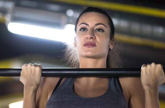 młoda muskularna kobieta robi podciąganie na drążku w ramach treningu cross fitness