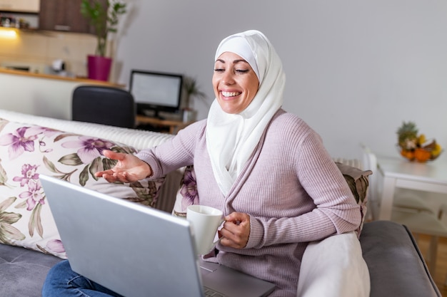 Młoda Muzułmanka ma rozmowę wideo przez laptop w domu