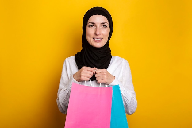 Młoda muzułmanka w hidżabie uśmiecha się i trzyma torby na zakupy