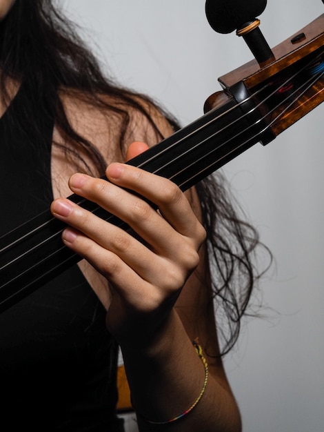 Zdjęcie młoda muzyka trzyma ręcznie wykonaną klasyczną wiolonczelę w rękach na stałym tle